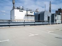 two buildings and one has a railing around it, both in the same spot of an industrial site