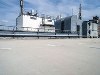 two buildings and one has a railing around it, both in the same spot of an industrial site