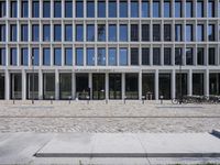 a brick building with glass windows and sidewalk leading to it and a black fire hydrant