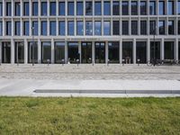 a brick building with glass windows and sidewalk leading to it and a black fire hydrant