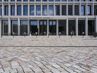 a brick building with glass windows and sidewalk leading to it and a black fire hydrant