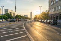 the sun is setting over an open street with traffic on both sides of it with cars parked in the parking lot