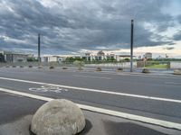 a bicycle lane on the street during a cloudy day and a person riding his bike in the road