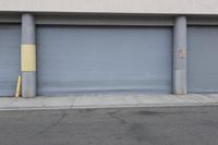an industrial steel closed garage door is on the side of a street next to a large building
