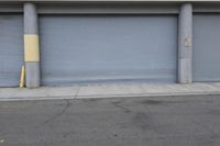 an industrial steel closed garage door is on the side of a street next to a large building