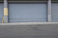 an industrial steel closed garage door is on the side of a street next to a large building