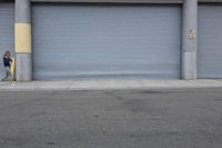 an industrial steel closed garage door is on the side of a street next to a large building