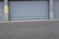 an industrial steel closed garage door is on the side of a street next to a large building