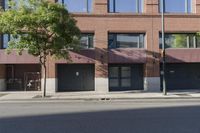 a building that has a tree in the front of it on a side walk by a street