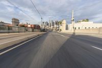 there is a road with buildings and wires in the background of this photo with a vehicle moving through the distance