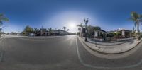 a 360 - degree photo of the street outside a restaurant and restaurant complex with tall palm trees in the background