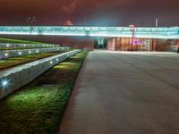 an outside area with a clock and green grass in the ground with lights illuminating up