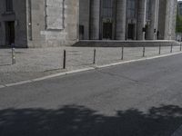 an old street that has some columns behind it and a person riding a motorcycle on the side