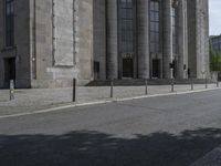 an old street that has some columns behind it and a person riding a motorcycle on the side