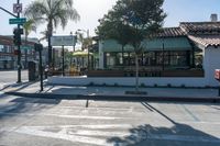 the crosswalk at an intersection has a few signs on it and people are waiting