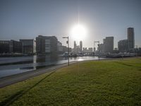 a city with green grass and other cars driving down it near water with tall buildings