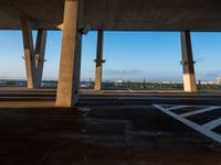 a large concrete structure with a sky background and view of the city from underneath it