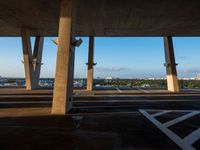 a large concrete structure with a sky background and view of the city from underneath it