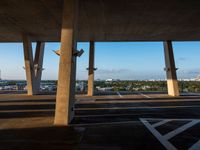 a large concrete structure with a sky background and view of the city from underneath it