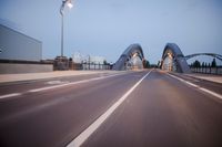 a long road next to a bridge with lights on it's sides and a street under them