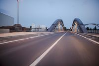 a long road next to a bridge with lights on it's sides and a street under them