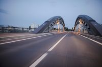 a long road next to a bridge with lights on it's sides and a street under them
