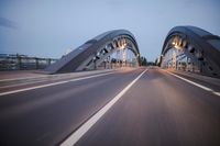 a long road next to a bridge with lights on it's sides and a street under them