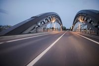 a long road next to a bridge with lights on it's sides and a street under them