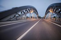 a long road next to a bridge with lights on it's sides and a street under them