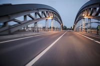 a long road next to a bridge with lights on it's sides and a street under them