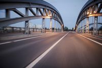a long road next to a bridge with lights on it's sides and a street under them