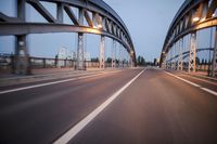 a long road next to a bridge with lights on it's sides and a street under them