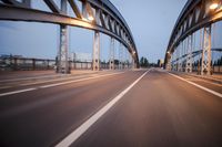 a long road next to a bridge with lights on it's sides and a street under them