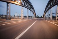 a long road next to a bridge with lights on it's sides and a street under them