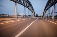 a long road next to a bridge with lights on it's sides and a street under them