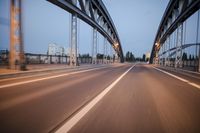 a long road next to a bridge with lights on it's sides and a street under them