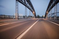 a long road next to a bridge with lights on it's sides and a street under them