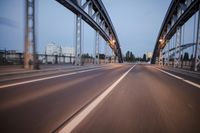 a long road next to a bridge with lights on it's sides and a street under them