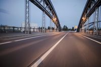 a long road next to a bridge with lights on it's sides and a street under them