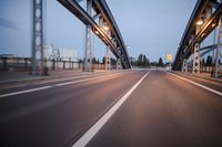 a long road next to a bridge with lights on it's sides and a street under them