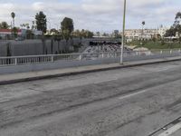 the side of the freeway has empty spaces with several lanes and railings, along with an overpass