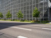 a street and some bushes near a building and traffic light at the same time of day