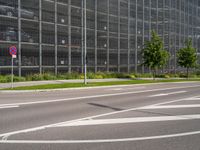 there are many cars parked behind the glassed building on the road, as well as a bike lane