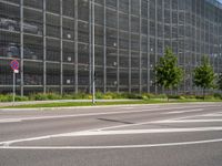 there are many cars parked behind the glassed building on the road, as well as a bike lane