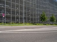 there are many cars parked behind the glassed building on the road, as well as a bike lane