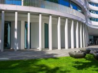 green grass, concrete steps and grass sculptures on the side of a building with columns