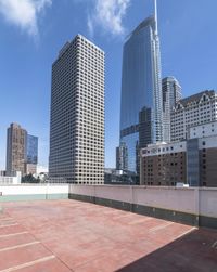 an empty parking lot with some high rise buildings in the background of the photo,