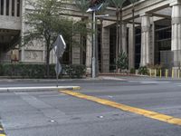 street scene with a view of an intersection and trees in the background of a tall building