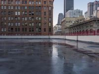 an urban setting, with one building in the background and a puddle of water in the parking lot