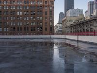 an urban setting, with one building in the background and a puddle of water in the parking lot